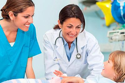 Nurse and doctor smiling to a child in hospital ward-stock-photo
