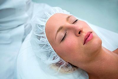 Patient lying on bed while receiving cosmetic treatment-stock-photo