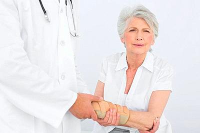 Male physiotherapist examining a senior woman's wrist in the medical office-stock-photo